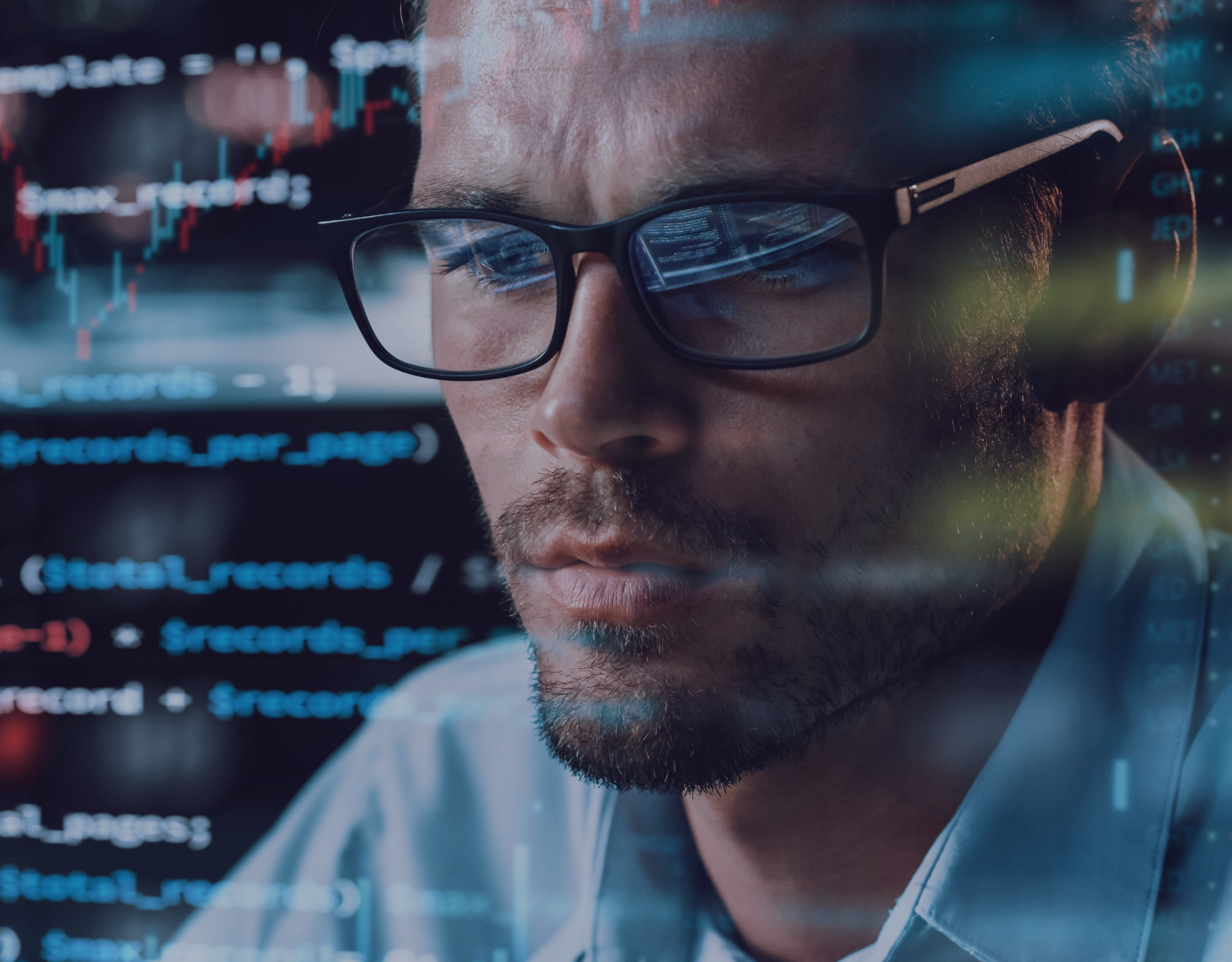 Man intensely looking at code on a computer screen, reflections in his eyeglasses